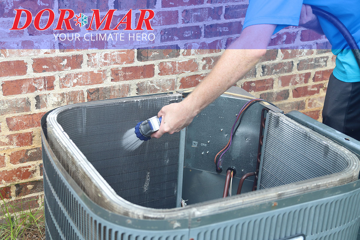 Dor-Mar service technician cleans inside and outdoor AC condenser unit